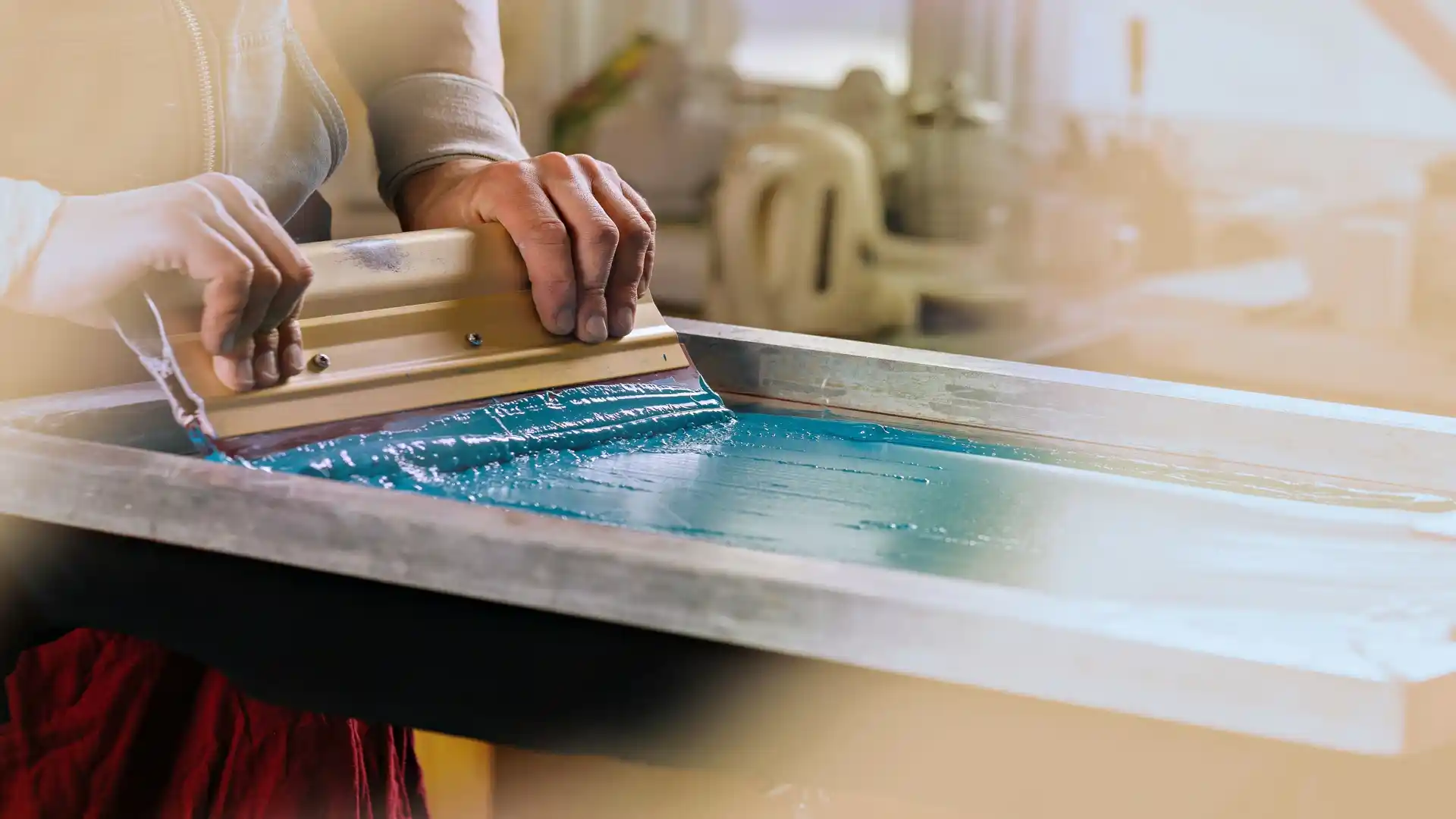 Screen printing a t-shirt with a squeegee pulling ink across a flat screen stencil