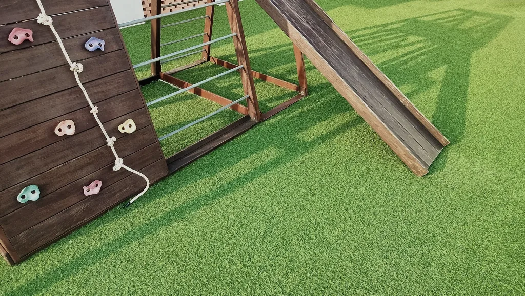 Artificial grass safety surface under a children's playground structure, designed in Pointcarre turf software